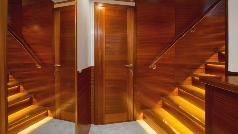 A wooden staircase with step lighting and banisters leads to the next floor.